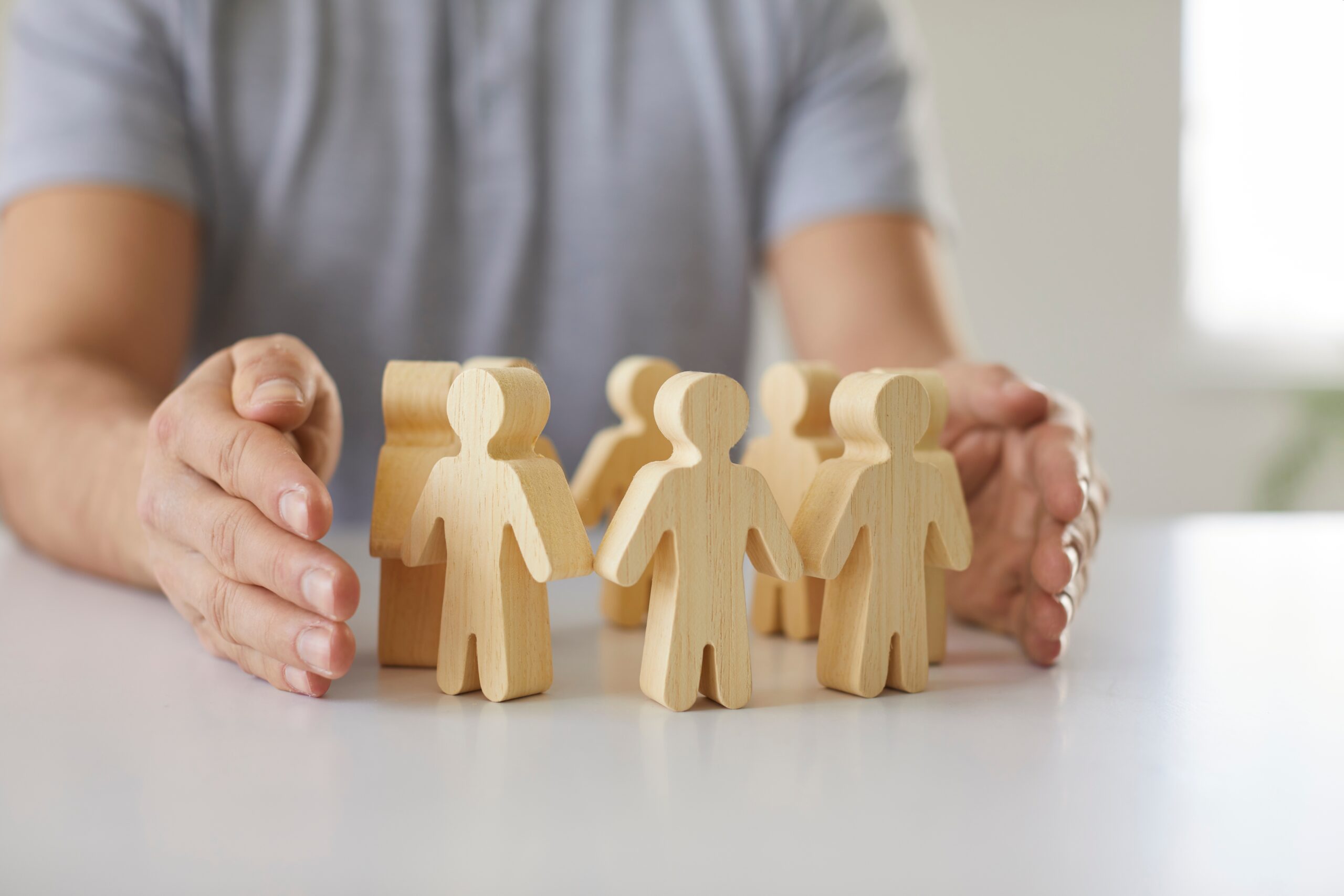 Man in blue shirt has 6 wooden men on table to demonstrate employment law changes in 2026